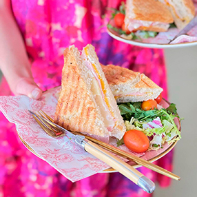 medarbejder holder sandwich på tallerken frem