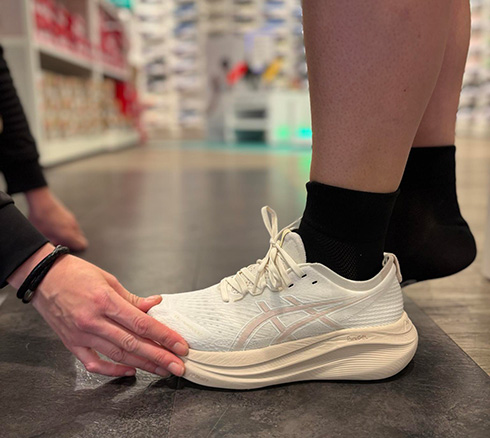 Medarbejder hjælper kunde med at prøve sko i butik